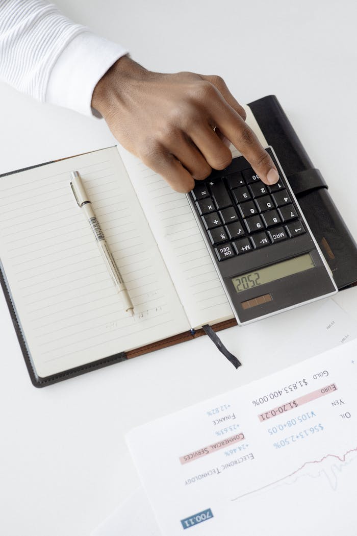 home-services-004 A hand using a calculator with financial documents and notebook, depicting an office setup for financial analysis.