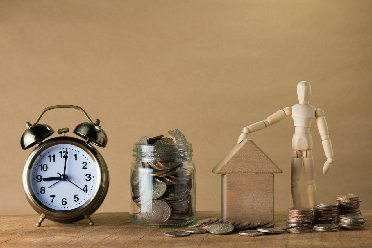 home-services-01 Wooden mannequin with a house, coins, and clock symbolizing time and financial planning.